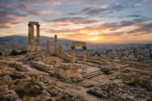 Ancient Roman stone ruins with columns and tourists walking nearby at sunset
